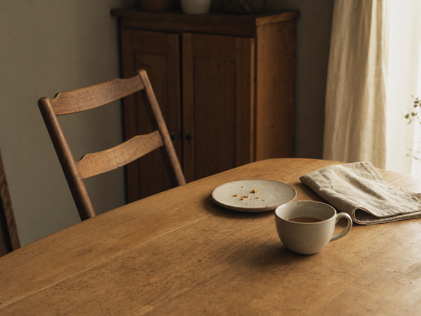 A dining table just after a meal, with an empty plate, a cup and a chair pushed back